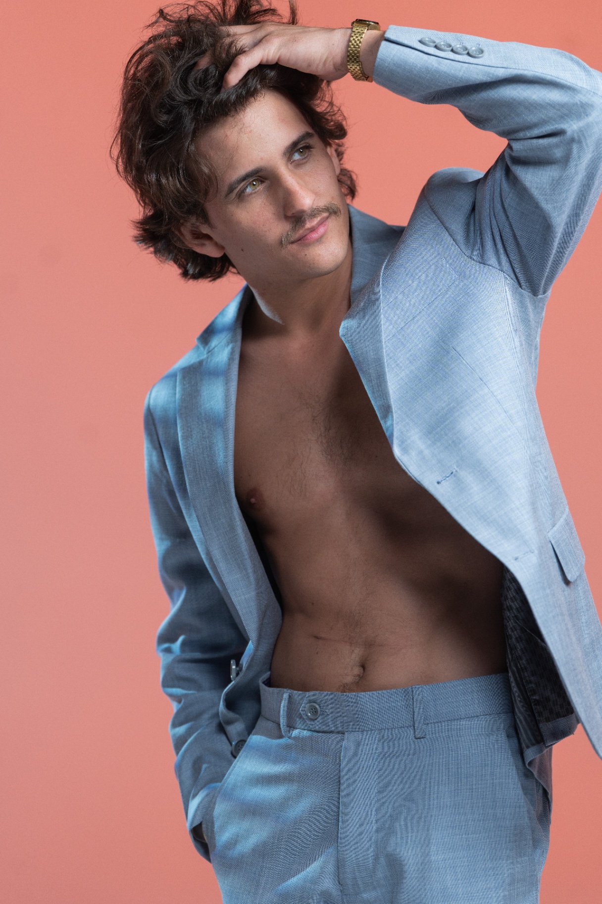 Montalvo posando con traje azul cielo sobre fondo coral