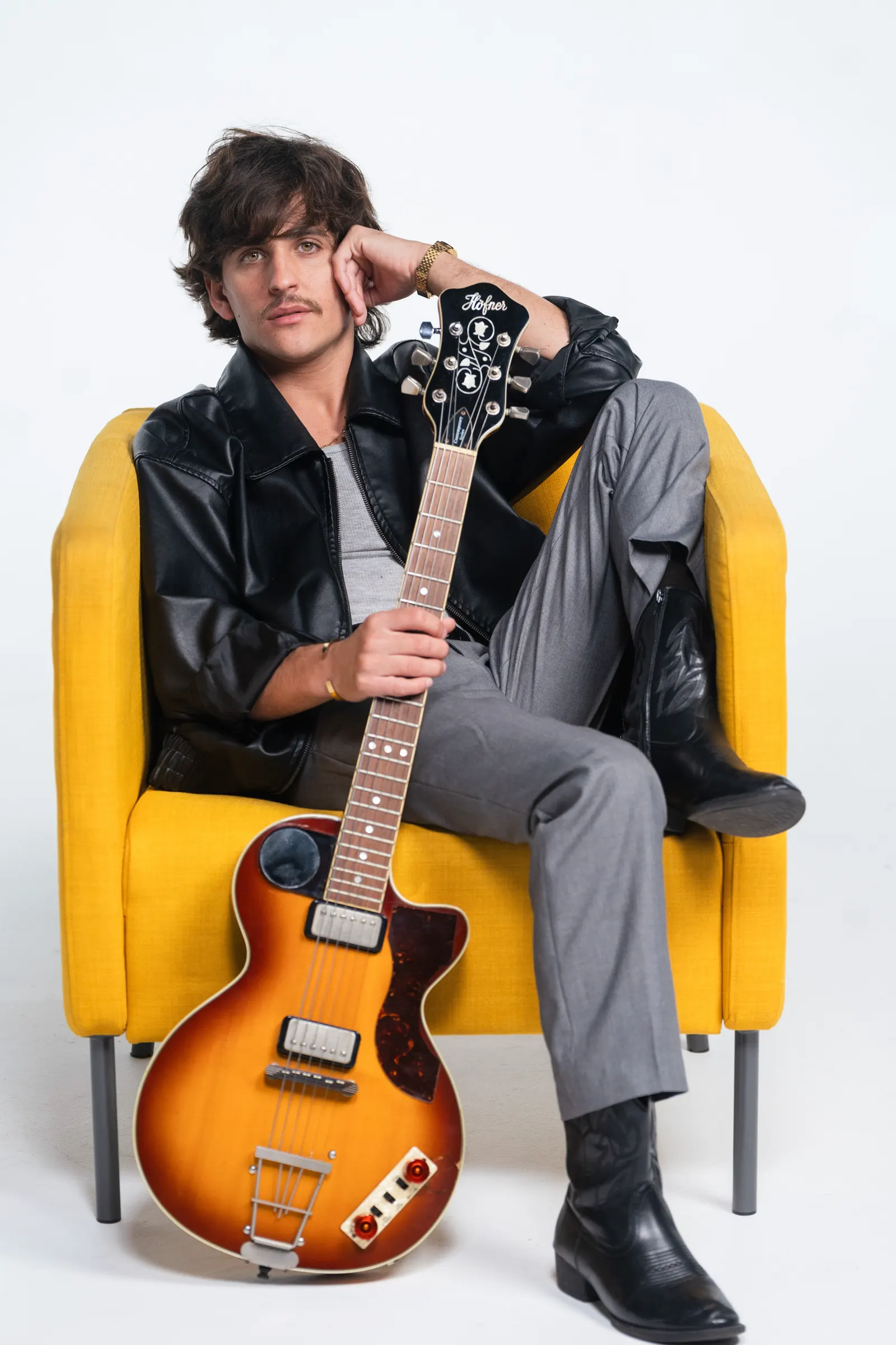 Montalvo sentado en sillón amarillo con guitarra Höfner